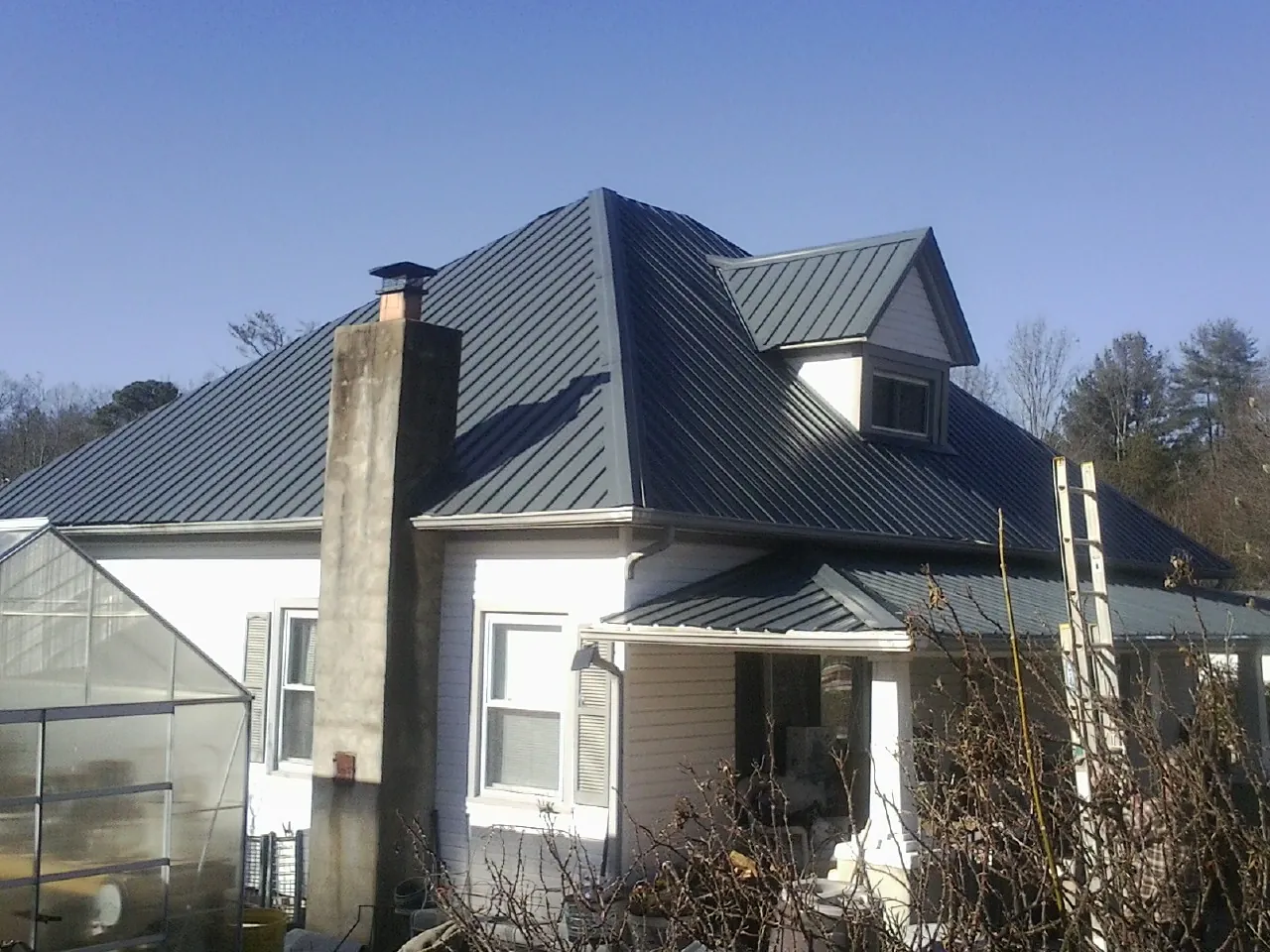 Dark blue standing seam metal roof on a white farmhouse with dormer — Slate & Tile Roof Repair by Roofing Brothers in Lincoln Park