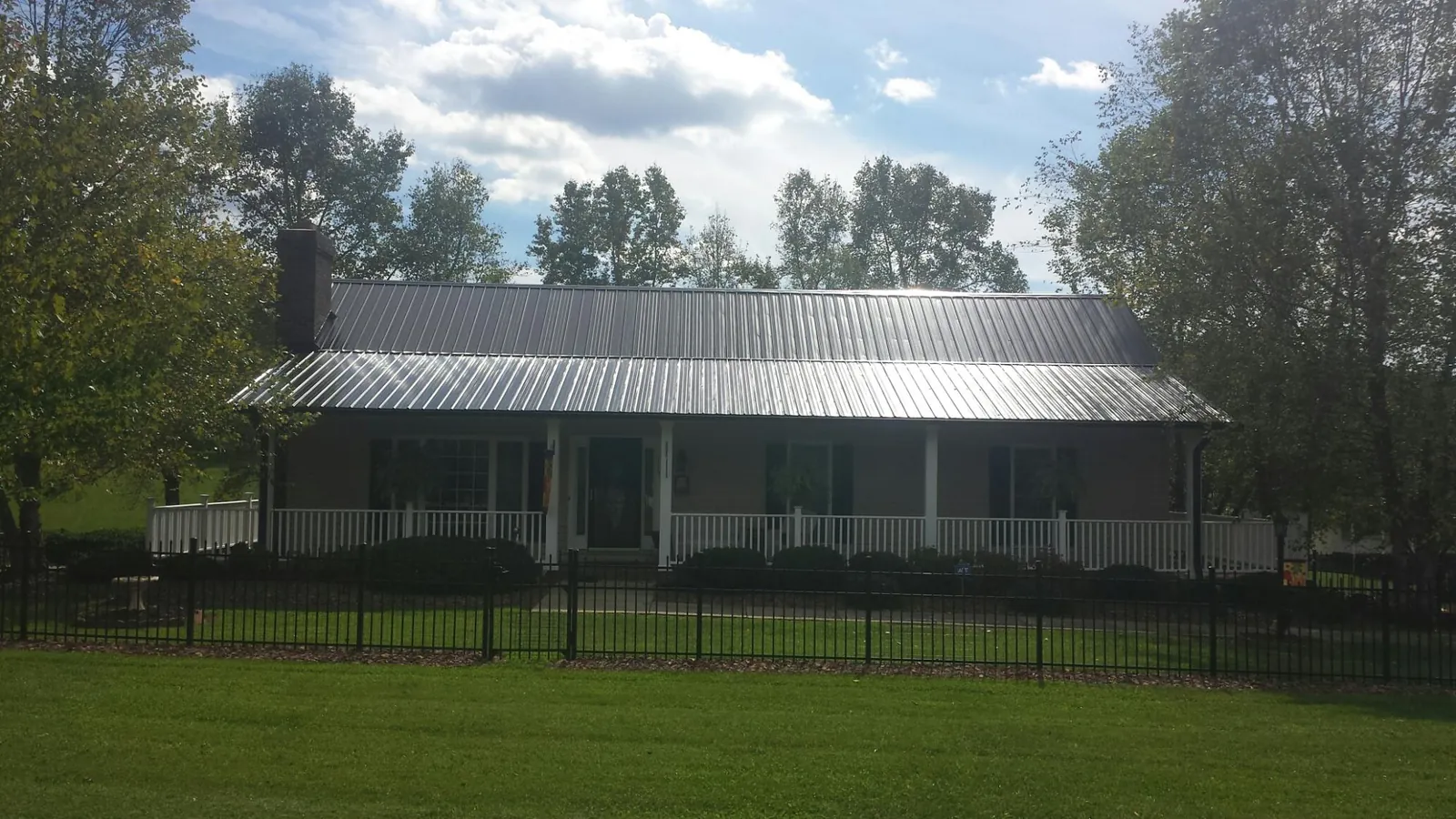 Gray metal roof on a brick ranch with a full width front porch — Gutter Guard Installation work by our crew in Lincoln Park