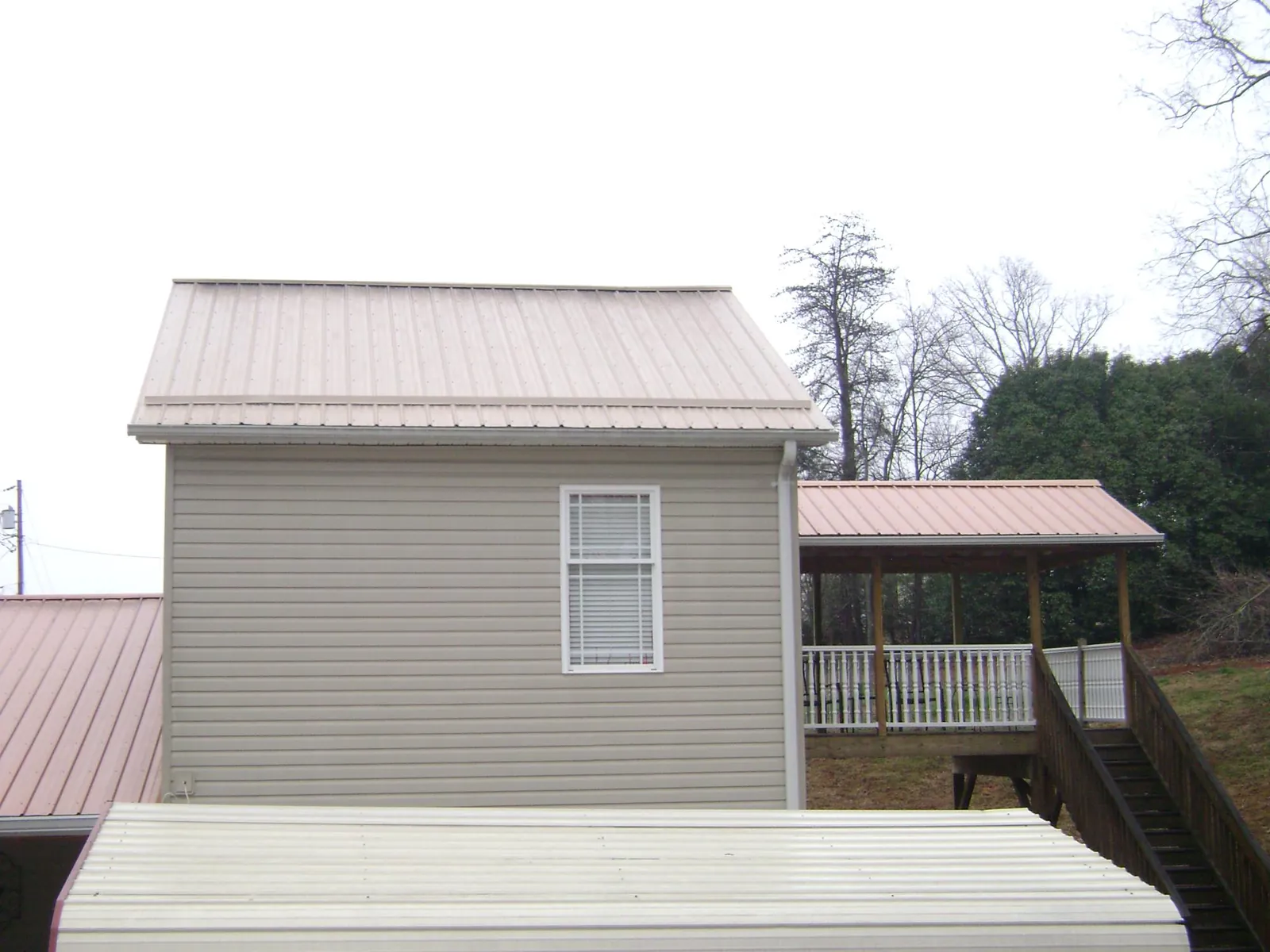 Tan metal roofs on a two story addition and attached porch, from a Roof Replacement job in Lincoln Park