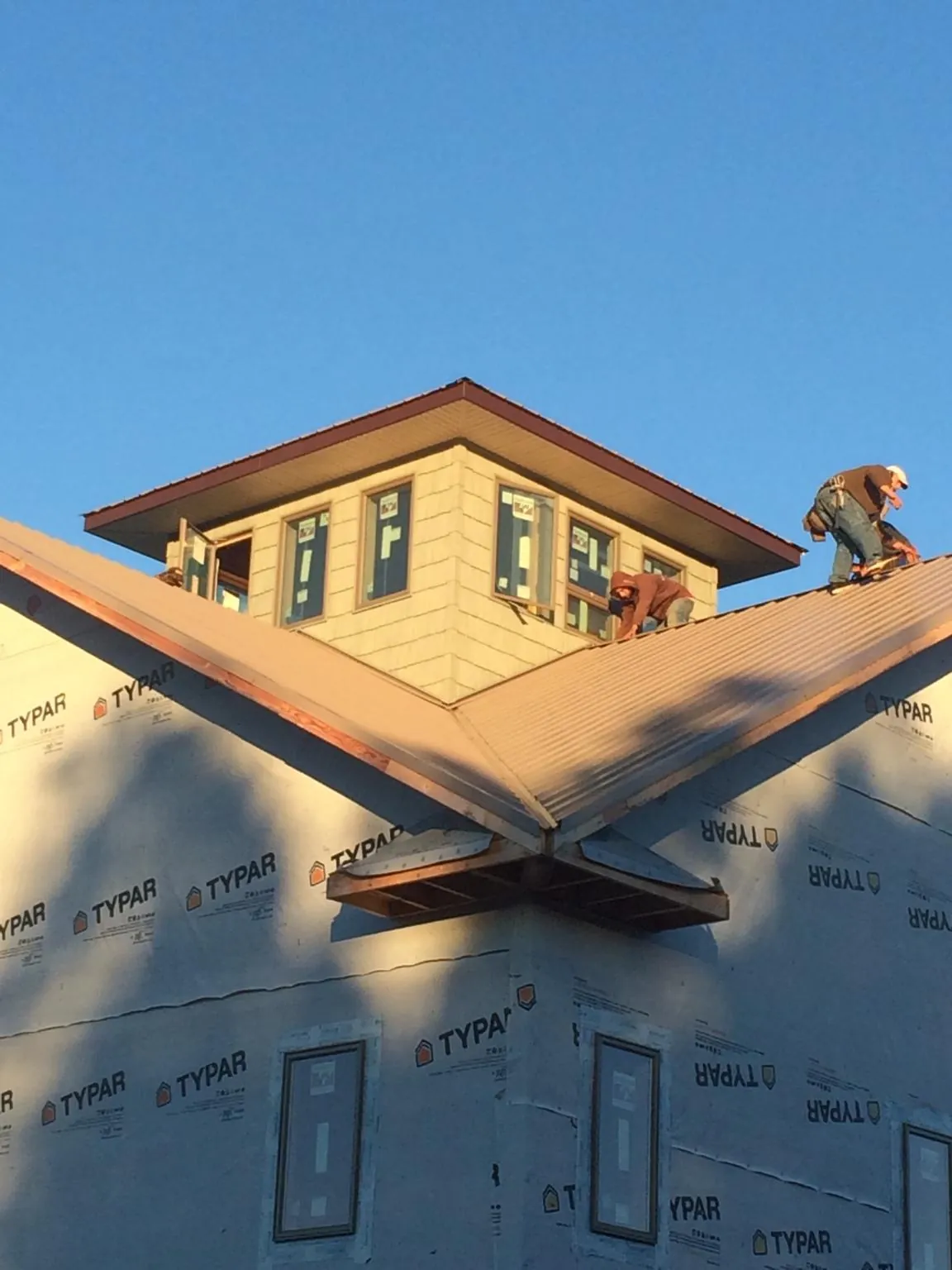 Roofers working around a rooftop cupola on a new metal roof at sunset — Roof Waterproofing in Lincoln Park by Roofing Brothers